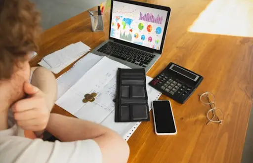 A guy watching a statistical chart on laptop with calculator