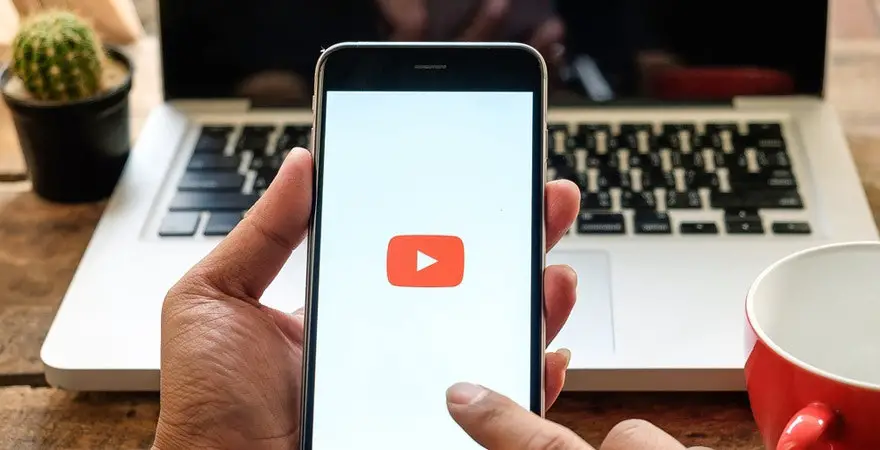 A hand holding a phone with youtube open