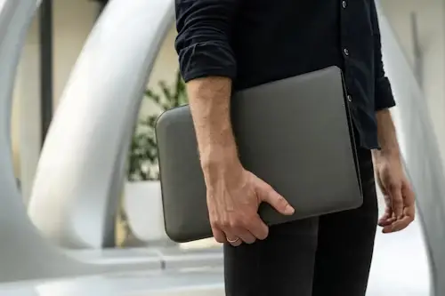 Man wearing black holding a laptop in a case